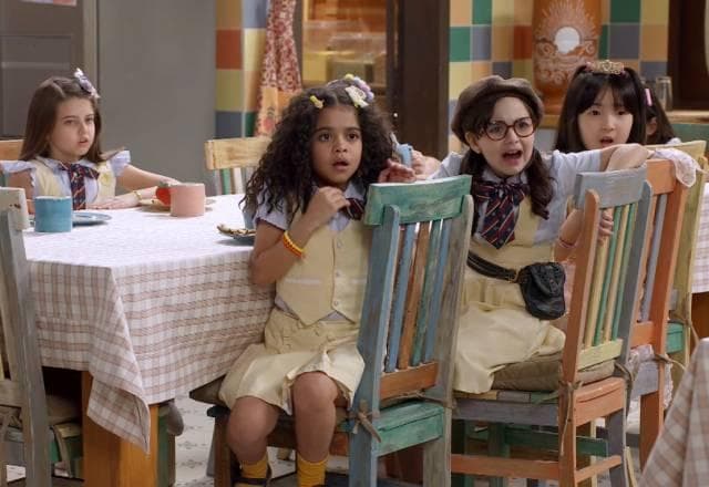 Meninas sentadas na mesa da cozinha e chocadas